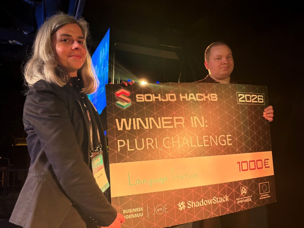 Alicja and Joonas hold a big check at the hackathon award ceremony